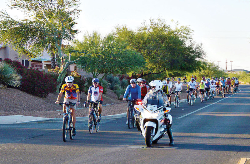Cyclists head down Abrego escorted by Pima County Sheriff