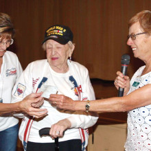 Honor Flight coordinator Kathy Mansur and WWII Veteran Helen Glass receive $1000 check from TWOQC President Peggy McGee.