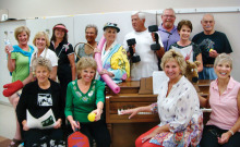Cyndy Gierada and Jeri Collins, seated at the piano, work with the singers as they present life at Quail Creek. How many activities can you identify?
