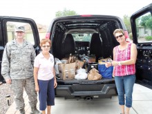 Left to right: Captain (Chaplain) Nathan Mestler, 162nd Wing, Arizona Air National Guard, TWOQC President Peggy McGee and 162nd Family Readiness Program Manager Barbara Gavre with just some of the food and household items that Quail Creek residents donated to show their support for the Airmen and their families; photo by Steve Abel.