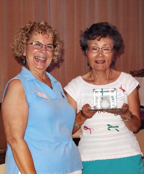 Mary Litfin smiles as Yoshie Hennessey shows the Hole-in-Oneder Crystal Golf Ball; photo by Sylvia Butler.