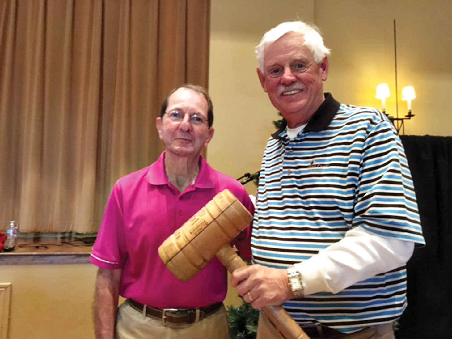 Outgoing President of the QCMGA Skip Fumia passes the gavel to incoming President Tim Phillips at the annual meeting.