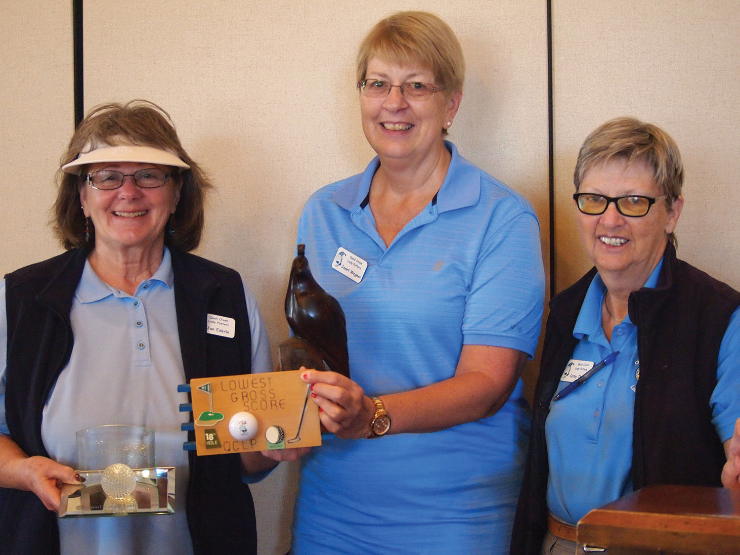 Jan Ederle holds the Crystal hole-in-one plaque and award plaque for the lowest gross score while Club Vice President Janet Wegner holds the Coveted Quail for low net score, with President Cathy Thiele looking on; photo by Sylvia Butler.