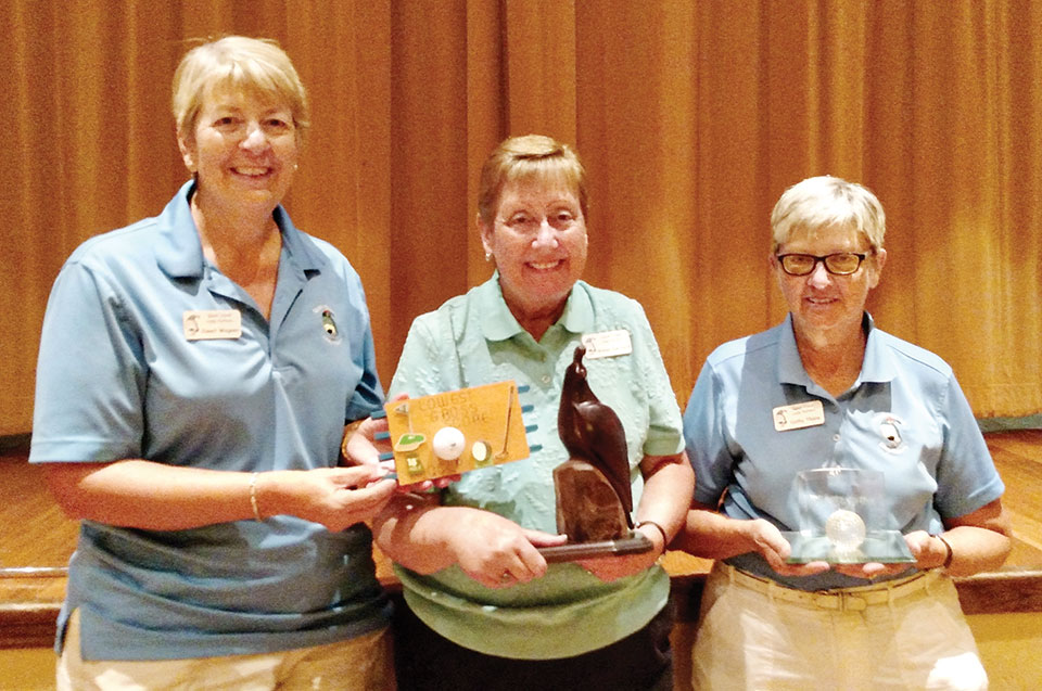 Left to right: Janet Wegner holds the Low Score plaque while Wendy Van Dyck holds the Coveted Quail. Cathy Thiele shows off the crystal golf ball for the most holes-in-one; photo by Sylvia Butler