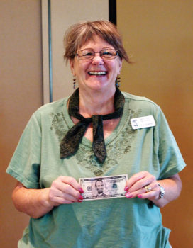 Jan Ederle is all smiles as she holds on tightly to her $5 bill; photo by Sylvia Butler.