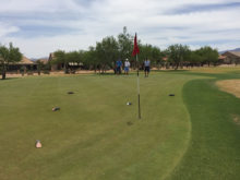 Revenge 1: David Ray, Jim Hart and Tommy Murray study tee markers that have found their way onto this green as immovable obstacles.