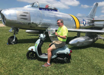 Bill Foraker relaxes in front of an F86 Sabre fighter jet while working the Warbirds area of EAA Oshkosh Airventure 2019.