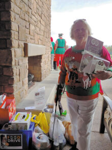 Pam Schroeder holds up the collection jar containing $450 in cash, check, and credit card donations; Photo by Peggy McGee.