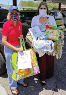 (Left to right) Peggy McGee and Karen Kuciver hold the layette items for the new baby and his mom. (Photo by Pat Crutcher)